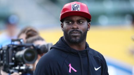 Michael Vick in a black hoodie and red cap poses for a picture.